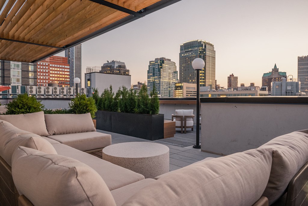 a living area with couches and a table on a balcony overlooking the city